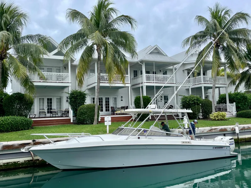The Image of 2001 Contender 35 Side Console boat docked by waterfront homes with palm trees. - 0