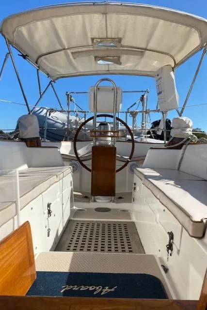 Slide: The Image of 1988 Shannon 43 sailboat cockpit with wooden wheel and canopy under clear blue sky. - 12