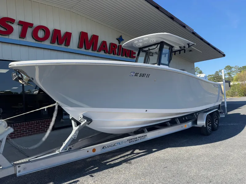 Slide: The Image of 2024 Sportsman Open 252 Center Console boat on trailer outside marine store. - 2