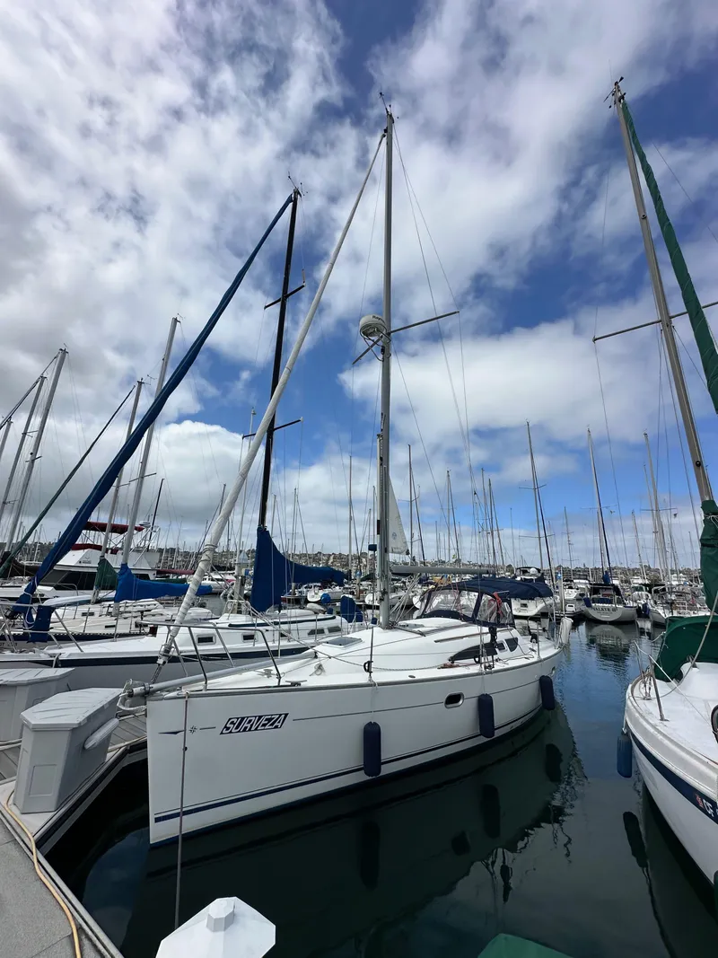 Slide: The Image of 2003 Jeanneau Sun Odyssey 32 sailboat docked in a marina under a cloudy sky. - 1