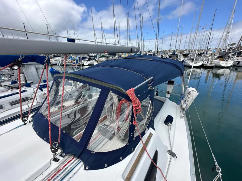 Slide: The Image of 2003 Jeanneau Sun Odyssey 32 sailboat docked in a marina, featuring a blue canopy. - 22