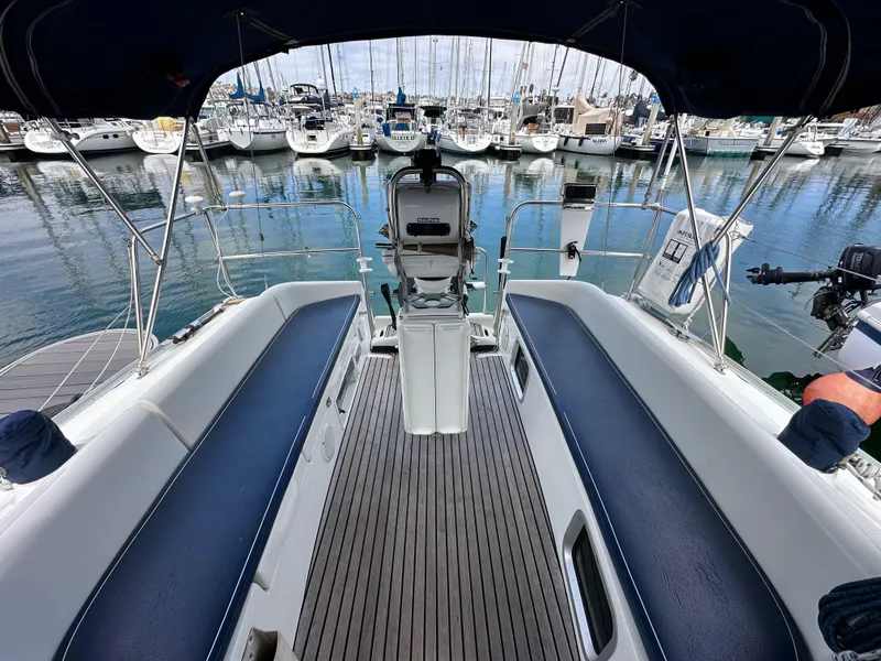 Slide: The Image of 2003 Jeanneau Sun Odyssey 32 sailboat cockpit with marina view, featuring blue seating and steering wheel. - 25