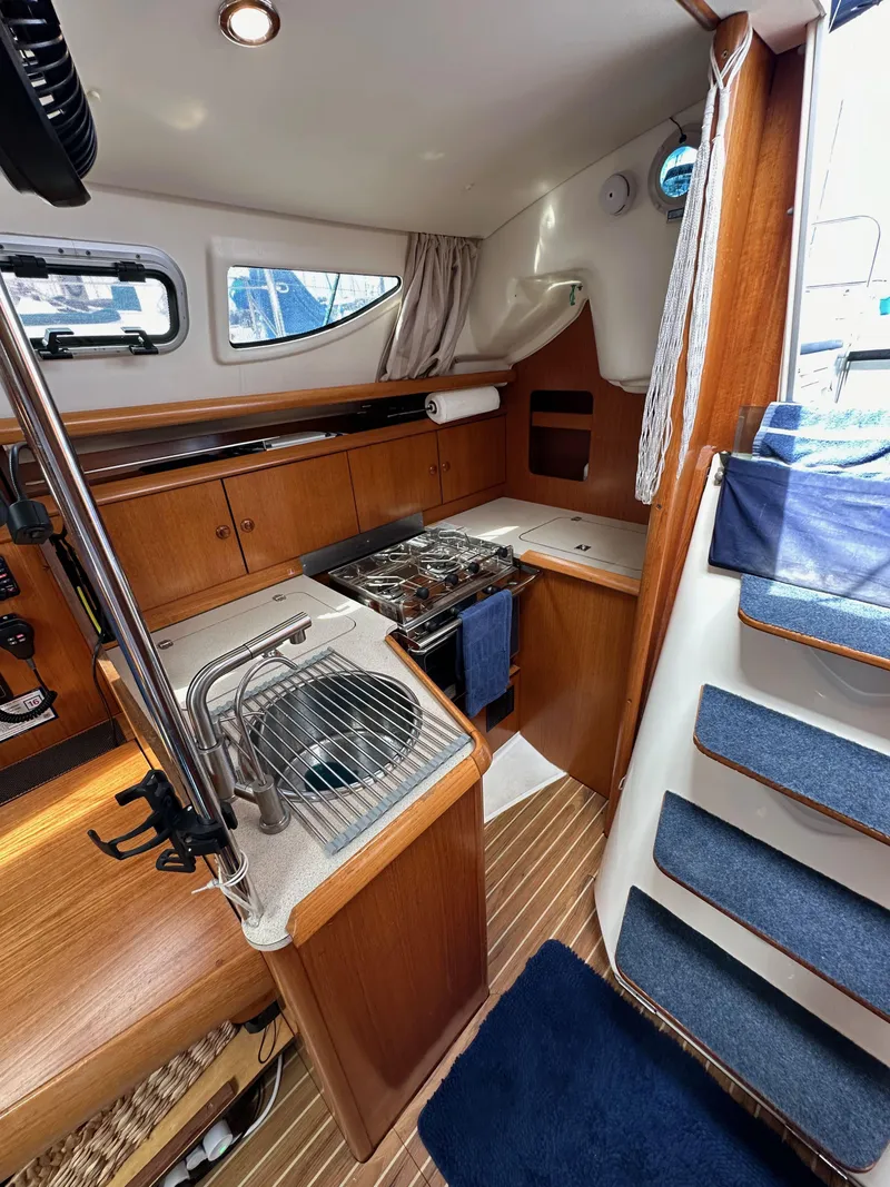 Slide: The Image of Interior of 2003 Jeanneau Sun Odyssey 32 sailboat, featuring compact kitchen and wooden cabinetry. - 45