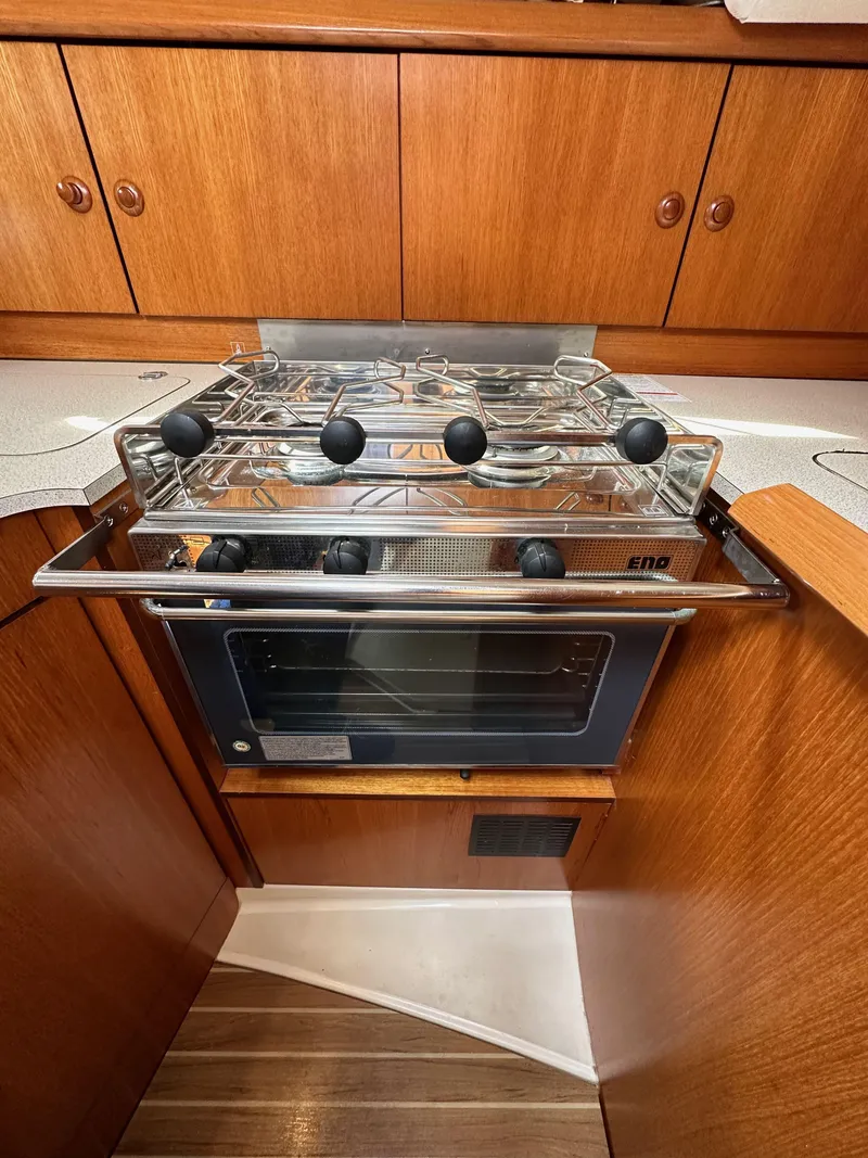 Slide: The Image of 2003 Jeanneau Sun Odyssey 32 yacht kitchen with stove and wooden cabinetry. - 48