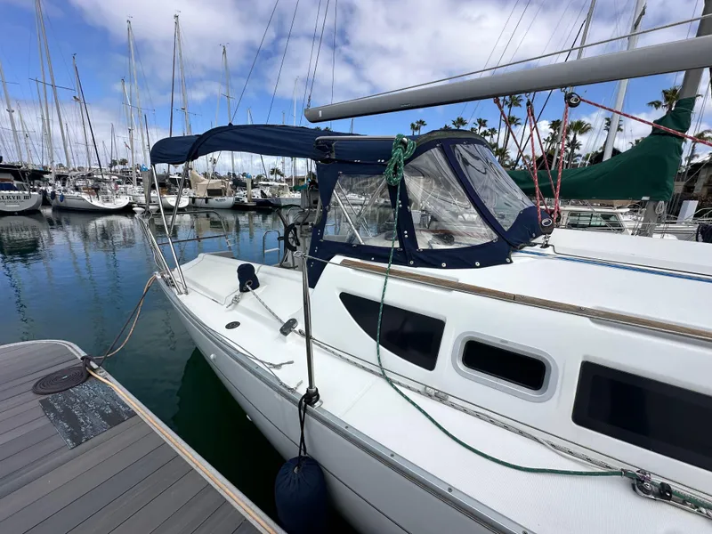 Slide: The Image of 2003 Jeanneau Sun Odyssey 32 sailboat docked in a marina, featuring a blue canopy. - 8