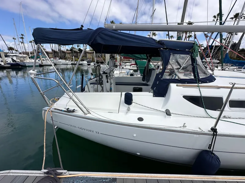 Slide: The Image of 2003 Jeanneau Sun Odyssey 32 sailboat docked in a marina, featuring a blue canopy. - 9