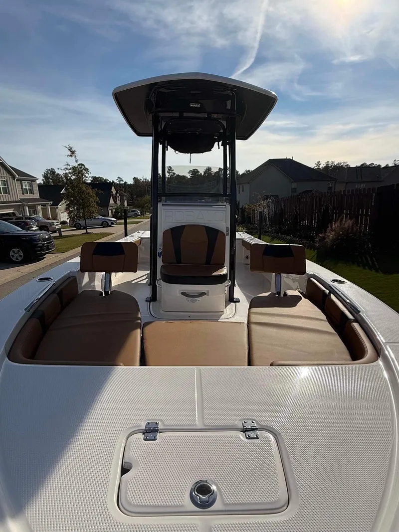Slide: The Image of 2024 Robalo 226 Cayman boat with cushioned seating and sleek design, parked in a residential area. - 10
