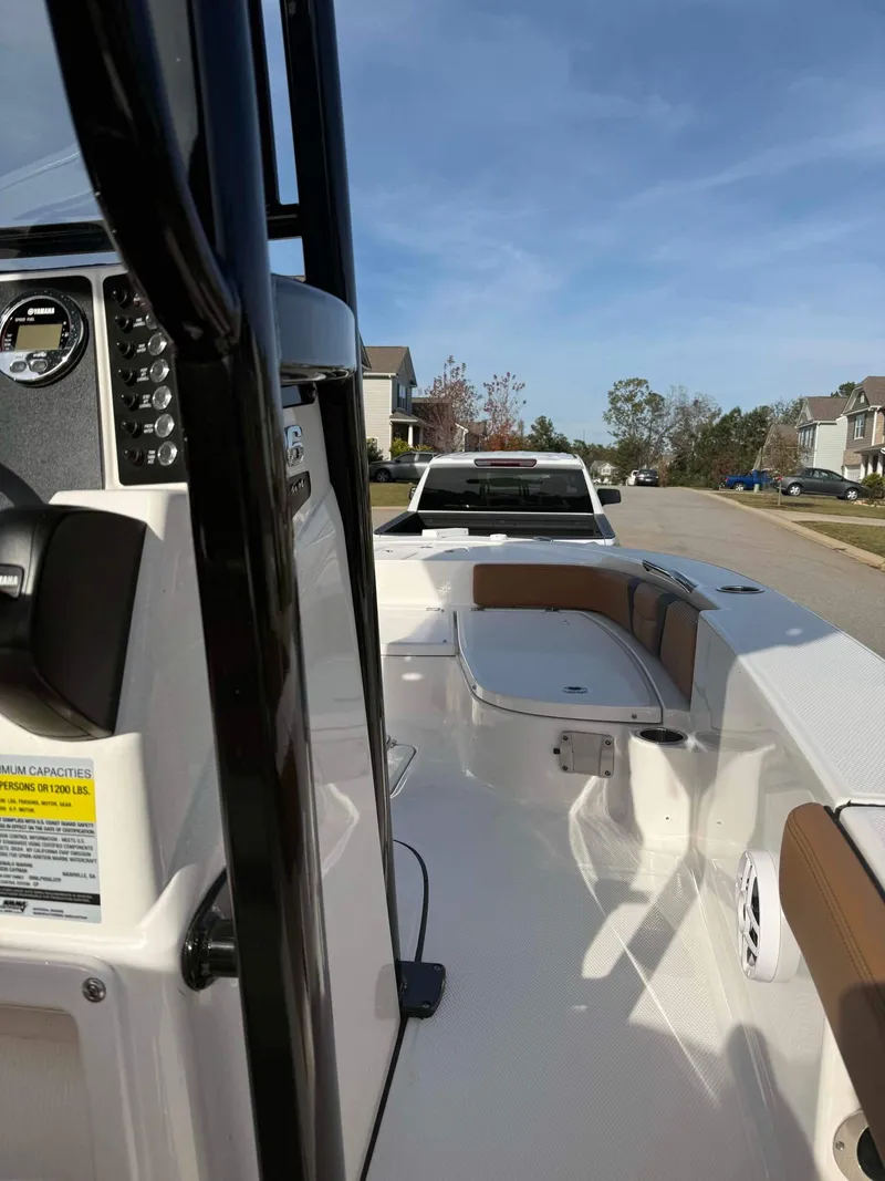 Slide: The Image of 2024 Robalo 226 Cayman boat interior with seating and console, parked on a residential street. - 5