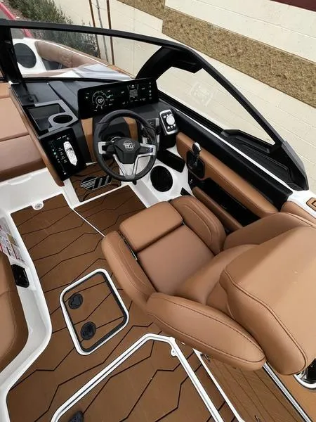 Slide: The Image of 2025 Malibu 24 MXZ boat interior with brown leather seats and modern dashboard. - 12