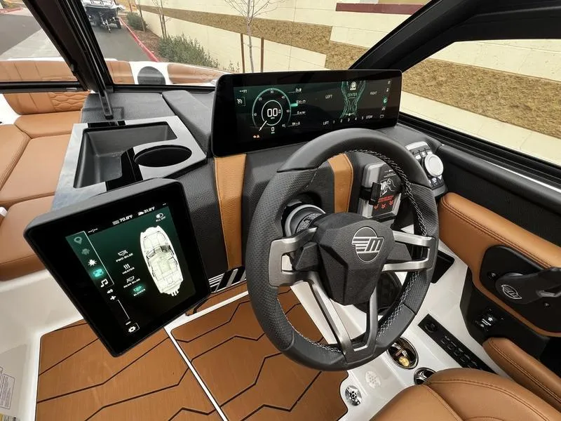 Slide: The Image of 2025 Malibu 24 MXZ boat dashboard with digital displays and modern steering wheel. - 13