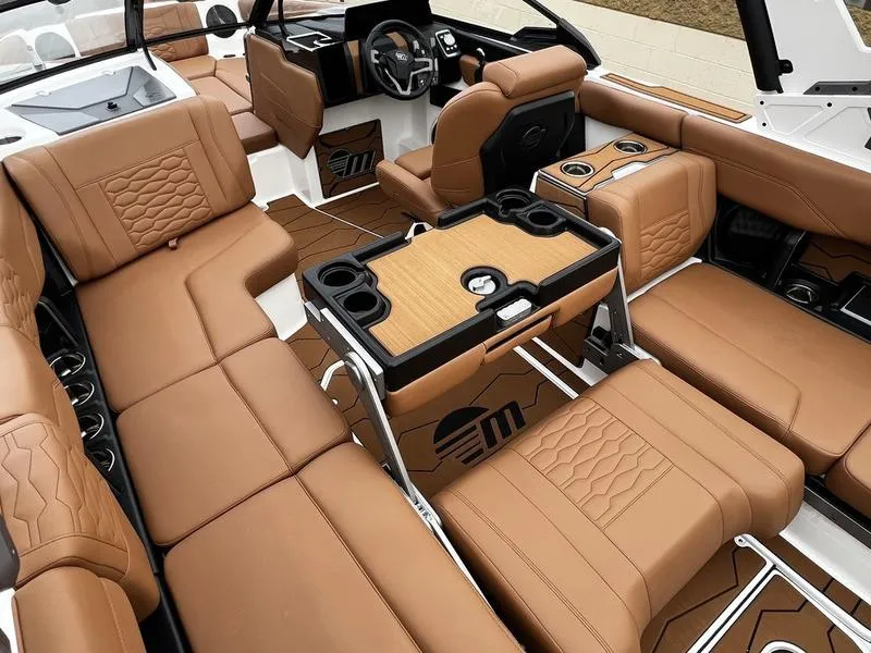 Slide: The Image of 2025 Malibu 24 MXZ boat interior with luxurious brown leather seating and modern design. - 23