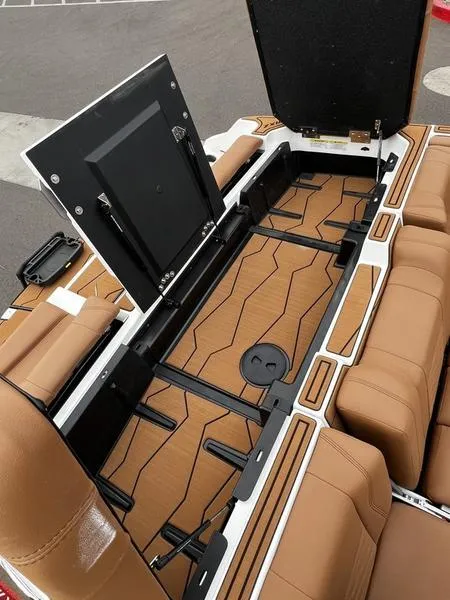 Slide: The Image of 2025 Malibu 24 MXZ boat interior with open storage compartment and tan seating. - 26