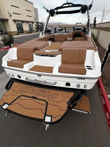 Slide: The Image of 2025 Malibu 24 MXZ boat with brown seating and sleek design, parked outdoors. - 8