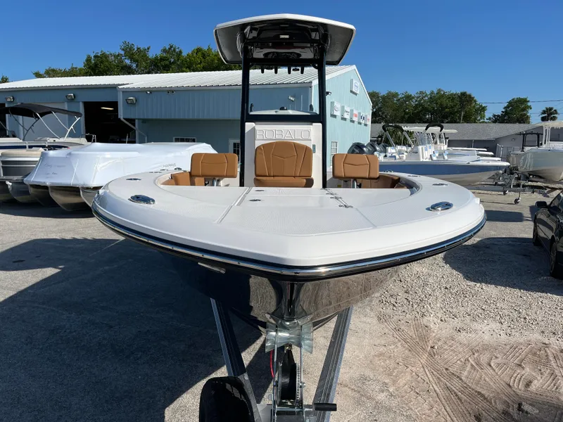 Slide: The Image of 2025 Robalo 246 Cayman boat, front view, parked outdoors near a warehouse. - 2