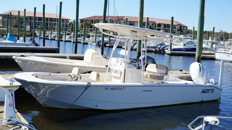 Slide: The Image of 2023 Carolina Skiff 24 Ultra Elite boat docked at marina with other vessels. - 1