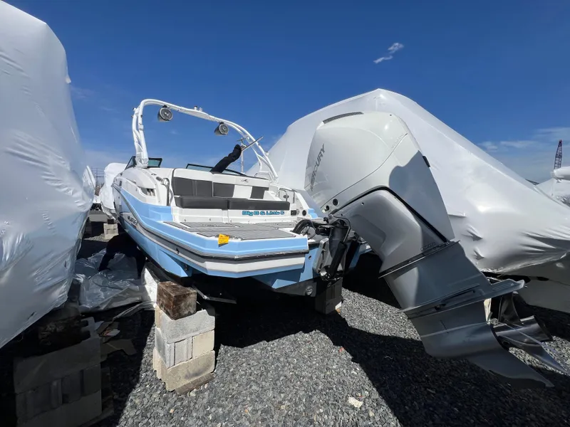 Slide: The Image of 2022 Monterey M65 boat on blocks, covered, with outboard motor, under clear blue sky. - 7