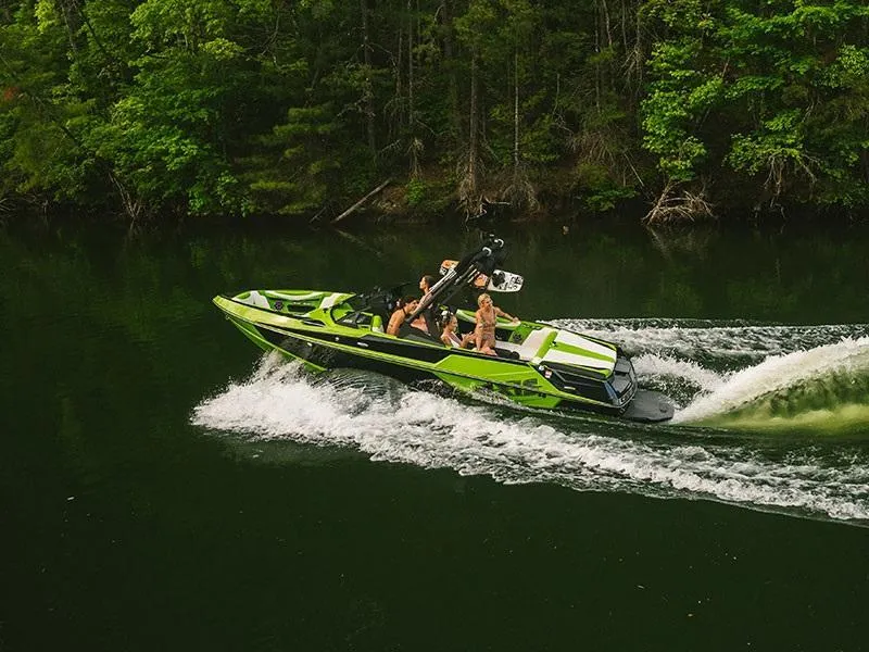 Slide: The Image of 2020 Axis T22 boat cruising on a lake surrounded by lush green trees. - 1