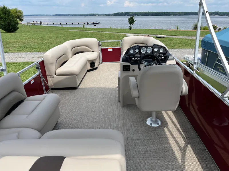 Slide: The Image of 2024 Landau Island Breeze 232 Cruise pontoon boat interior with plush seating and steering console. - 5