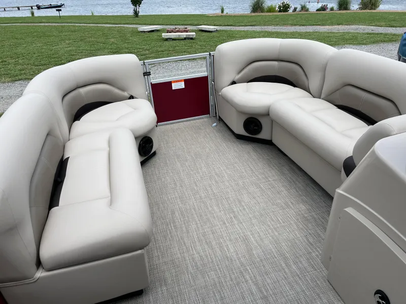 Slide: The Image of 2024 Landau Island Breeze 232 Cruise pontoon boat with beige seating, near a lakeside. - 8