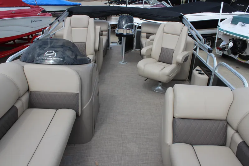 Slide: The Image of 2023 Sun Tracker Party Barge 22 DLX interior with beige seating and helm. - 12