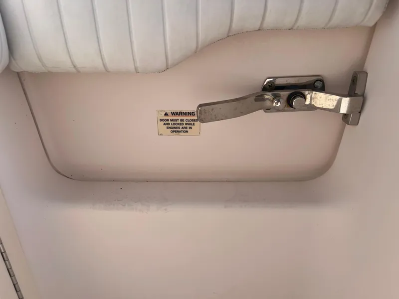 Slide: The Image of 2007 Grady-White Tournament 275 boat interior with a metal latch and warning label. - 26