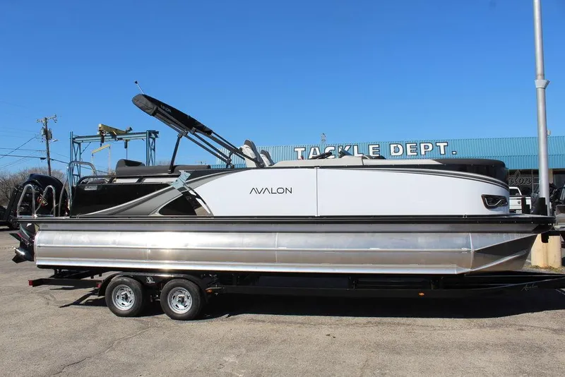 Slide: The Image of 2025 Avalon LSZ Quad Lounge Shift 25 FT pontoon boat on trailer, parked outdoors. - 1