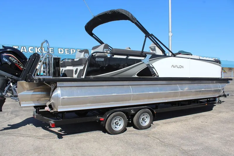 Slide: The Image of 2025 Avalon LSZ Quad Lounge Shift 25 FT pontoon boat on trailer, outdoor display. - 2