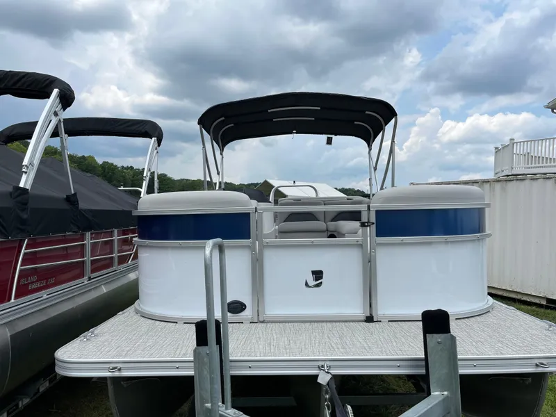 Slide: The Image of 2024 Landau Island Breeze 232 Cruise pontoon boat with canopy, docked under cloudy sky. - 3