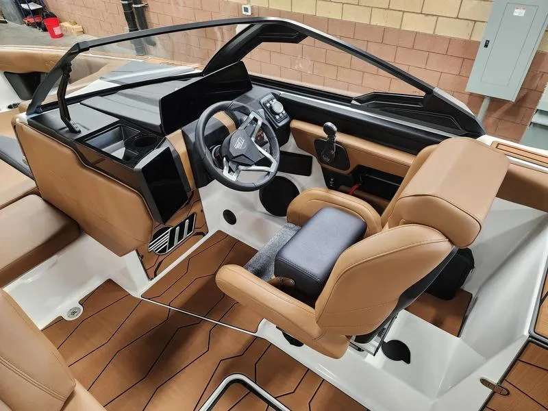 Slide: The Image of 2025 Malibu 24 MXZ boat interior with modern dashboard and tan seating. - 12