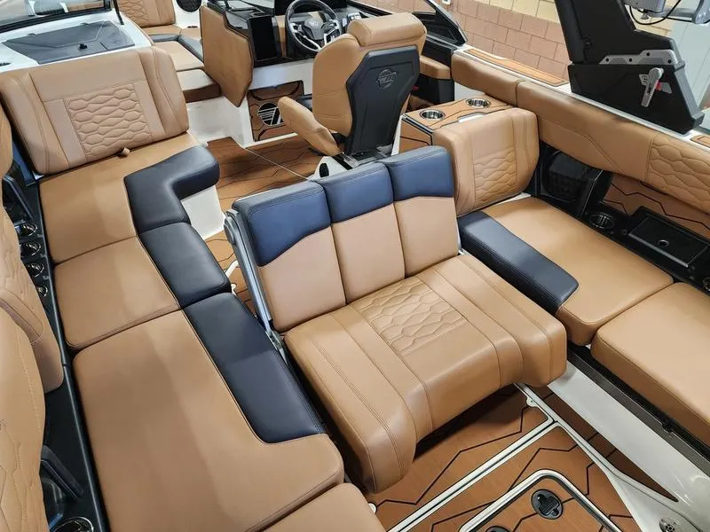 Slide: The Image of Luxurious interior of 2025 Malibu 24 MXZ boat with tan and black seating. - 20