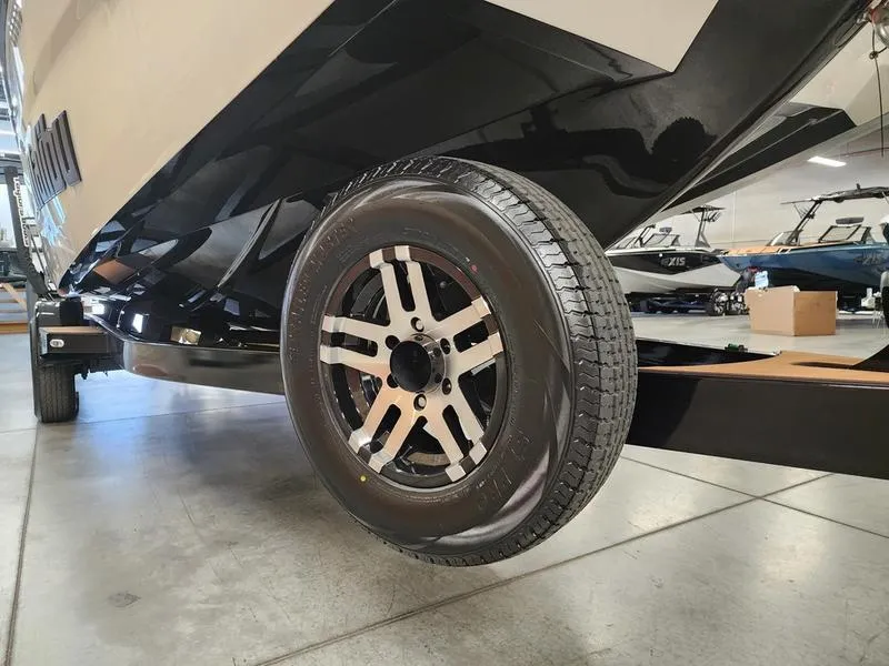 Slide: The Image of 2025 Malibu 24 MXZ boat trailer wheel in showroom setting. - 28
