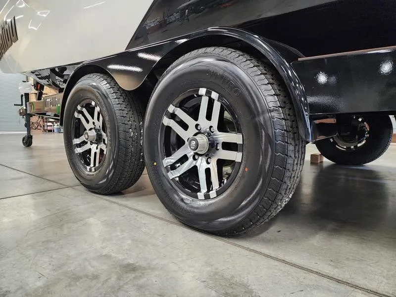 Slide: The Image of 2025 Malibu 24 MXZ trailer wheels in a showroom setting. - 3