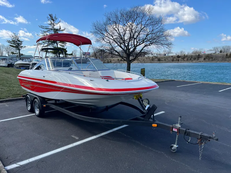 Slide: The Image of 2006 Tahoe 204 WT boat with red accents on a trailer by a lake. - 2