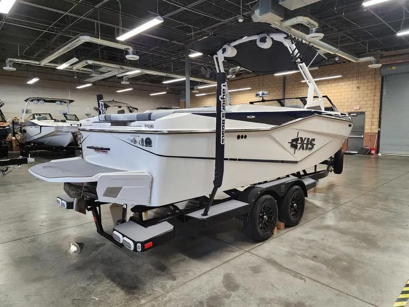 Slide: The Image of 2025 Axis T235 boat in showroom, featuring sleek design and dual-axle trailer. - 4