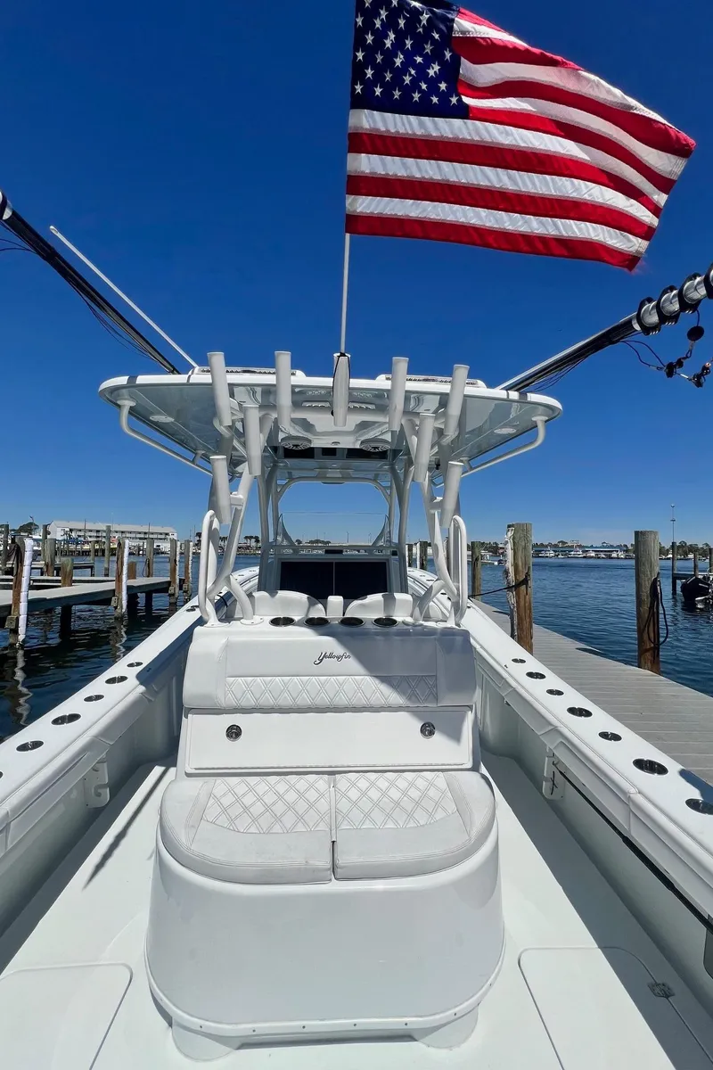Slide: The Image of 2021 Yellowfin 36 Offshore boat with American flag, docked under clear blue sky. - 16