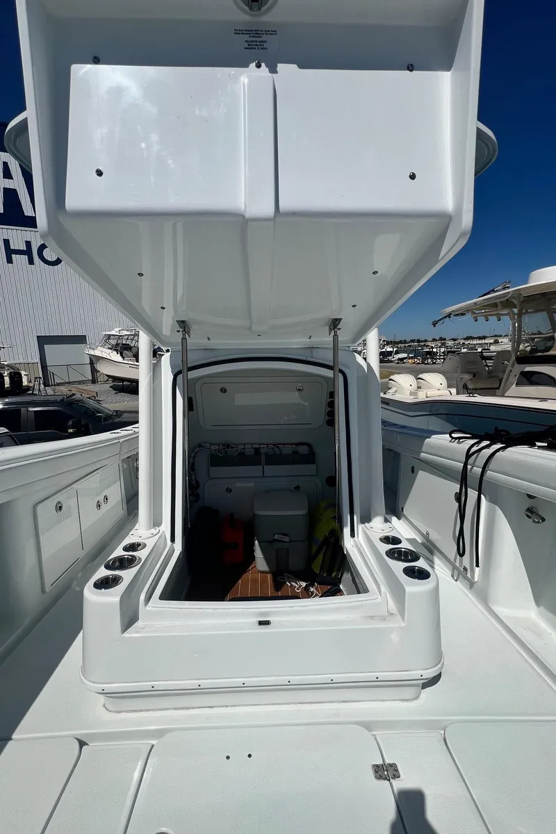 Slide: The Image of 2021 Yellowfin 36 Offshore boat with open storage compartment, docked under clear blue sky. - 25
