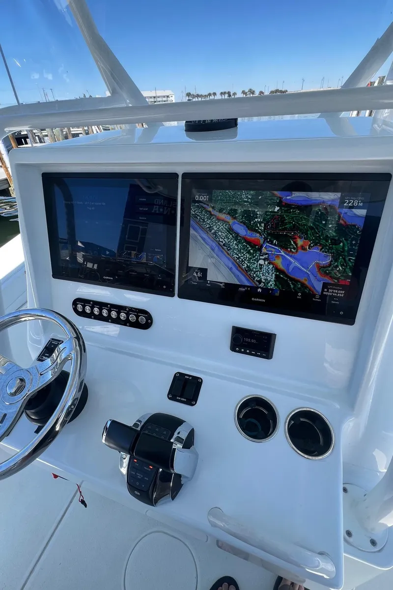 Slide: The Image of 2021 Yellowfin 36 Offshore boat dashboard with dual navigation screens and steering wheel. - 9