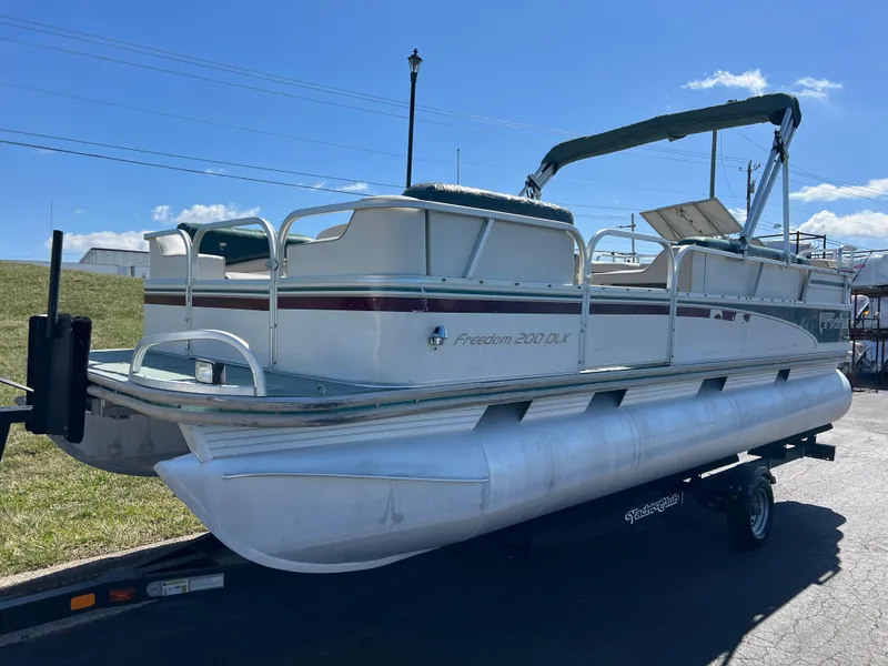 Slide: The Image of 1998 Fisher Freedom 200 DLX pontoon boat on trailer under clear blue sky. - 9