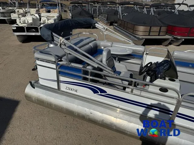Slide: The Image of 2011 TMC 2200 SE Pontoon boat in storage lot, featuring blue and white design. - 31