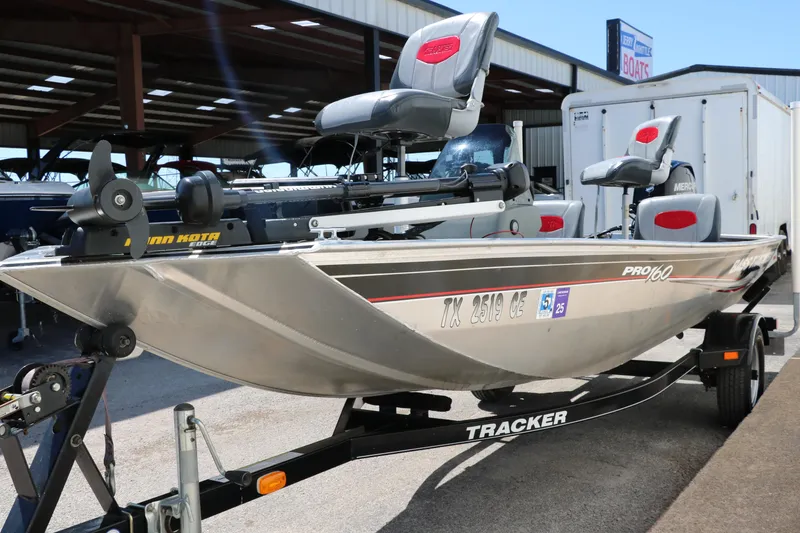 Slide: The Image of 2014 Tracker Pro 160 boat on trailer, featuring dual seats and motor, parked outdoors. - 8