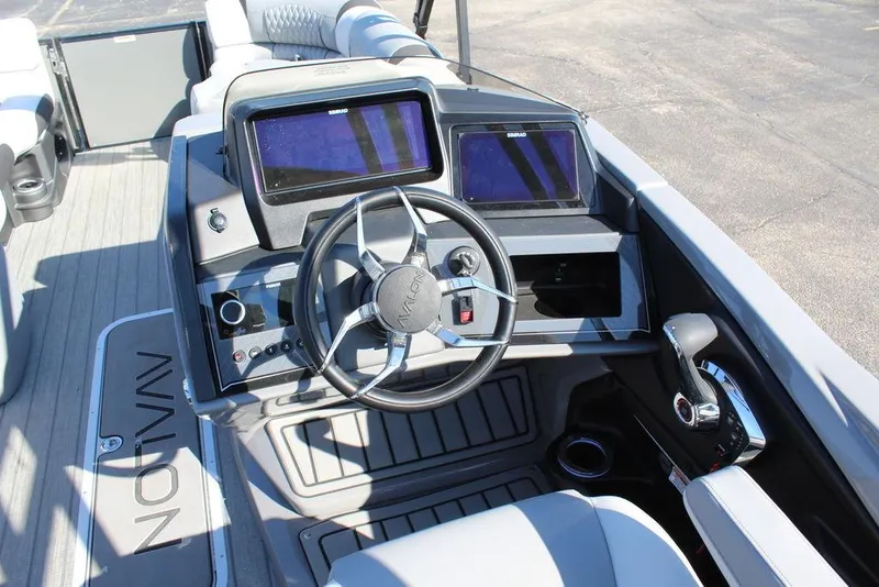 Slide: The Image of 2025 Avalon Excalibur LTD Quad Lounge 25 FT boat dashboard with steering wheel and dual screens. - 13