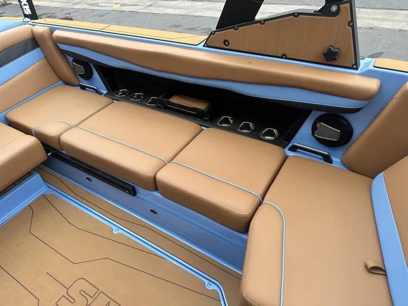 Slide: The Image of 2024 Axis A225 boat interior with tan and blue seating, cup holders, and sleek design. - 11