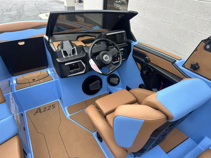 Slide: The Image of 2024 Axis A225 boat interior with blue and tan seating, modern dashboard, and steering wheel. - 12