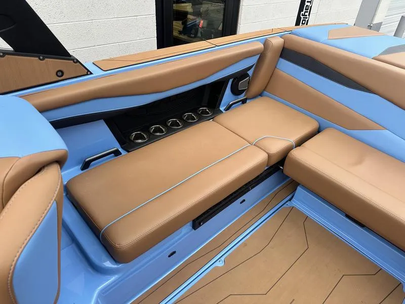 Slide: The Image of 2024 Axis A225 boat interior with tan and blue seating, featuring cup holders. - 13