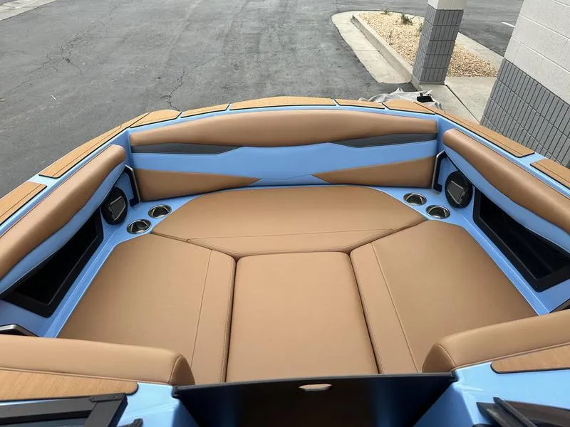 Slide: The Image of 2024 Axis A225 boat interior with tan and blue seating, cup holders, and speakers. - 16