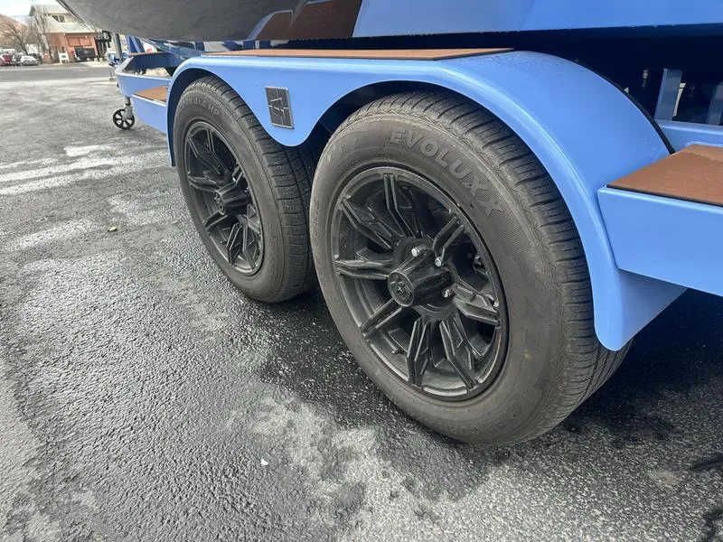 Slide: The Image of 2024 Axis A225 trailer with black wheels on a textured asphalt surface. - 6