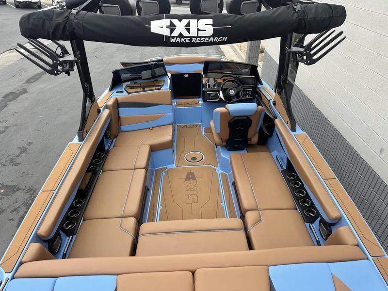Slide: The Image of 2024 Axis A225 boat interior with tan and blue seating, featuring Axis Wake Research branding. - 9