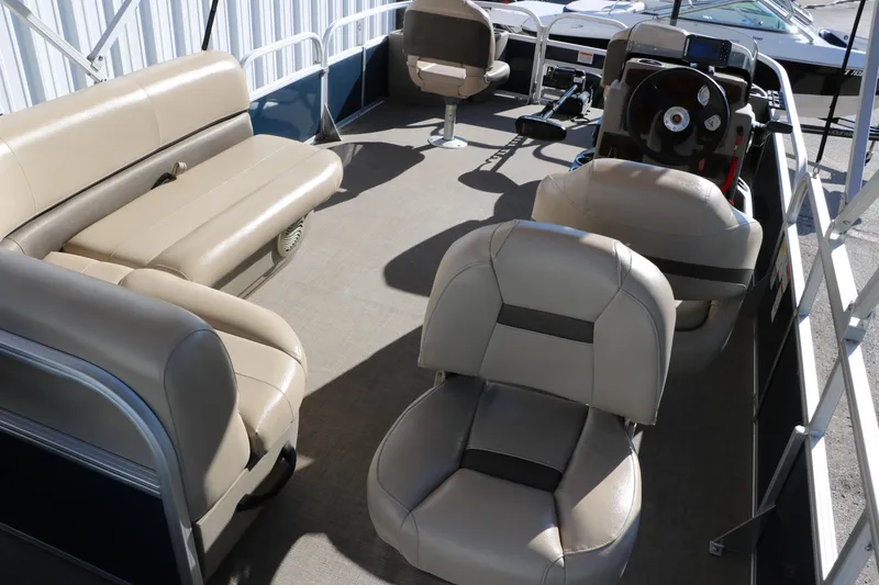 Slide: The Image of 2023 Sun Tracker Bass Buggy 18 DLX interior with beige seating and steering console. - 20