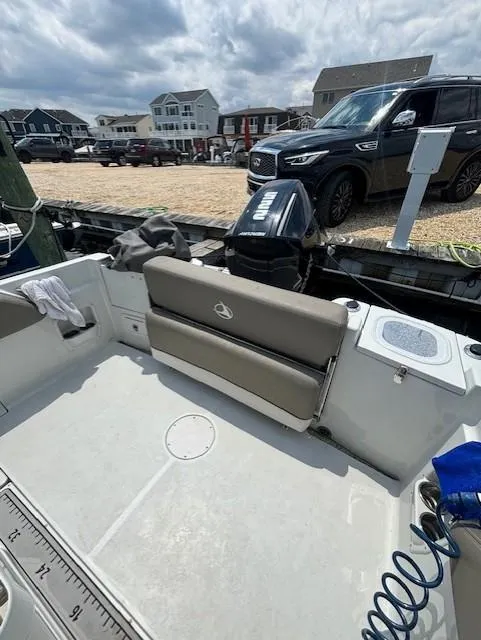 Slide: The Image of 2022 Finseeker 230 CC boat interior with seating, docked near vehicles and houses. - 12