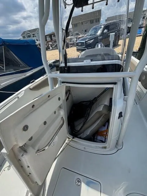 Slide: The Image of 2022 Finseeker 230 CC boat with open storage compartment, docked near other boats. - 14